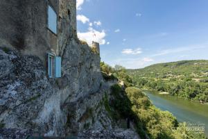 a building on the side of a cliff next to a river at Le Château d'Aiguèze in Aiguèze