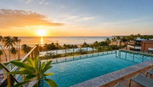 a pool with a view of the ocean at sunset at Jardins Almare Apart Hotel in João Pessoa