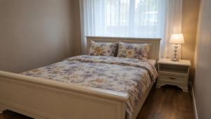 a bed in a bedroom with a window and a lamp at Centro apartamentai in Zarasai