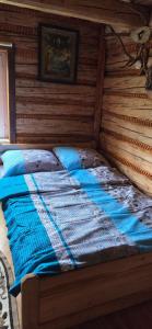 a bed in a room with a wooden wall at Chata Między Górami in Zalesie