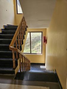 a staircase in a house with a window at Hotal DESPRADES MRITYUNJAY INN in Jageshwar +1 photo