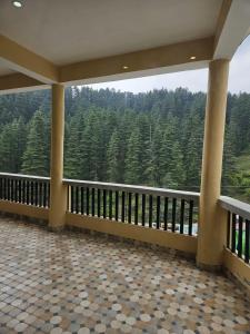 a balcony with a view of a forest of trees at Hotal DESPRADES MRITYUNJAY INN in Jageshwar