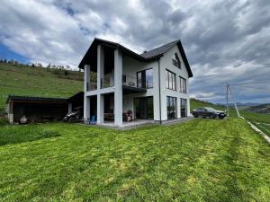 a white house with a car parked in a field at SoTA SKI in Pilipets