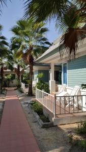 a house with white chairs and palm trees in front of it at Vipha Ville Resort in Ban Huai Yang