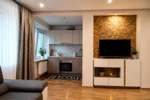 a living room with a television and a kitchen at Centro apartamentai in Zarasai