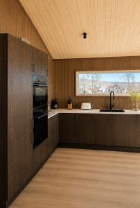 a kitchen with wooden cabinets and a sink and a window at Jarfjord Nature Escape in Herjenes