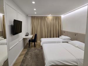 a hotel room with two beds and a desk at Hotel IN in Žepče