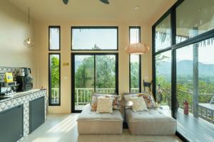 a living room with a couch and a table and windows at Archie Paradise View in Thong Sala