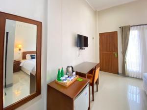 a hotel room with a bed and a desk and a mirror at Urbanview Hotel Ratna Syariah in Sukobumi