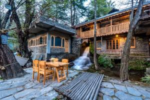 a wooden table and chairs in front of a house at NotOnMap - H2O House in Chamba