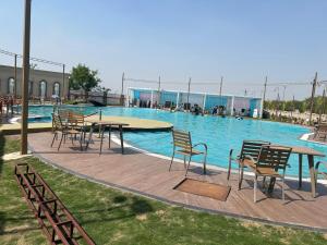 a pool with tables and chairs in front of it at Vetiver Grand in Jabalpur