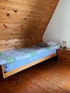 a bed in a room with a wooden wall at Agroturystyka Iwona Jażdżewska in Osława Dąbrowa