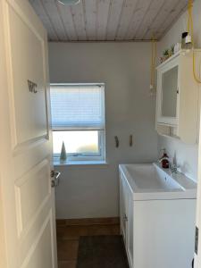 a white bathroom with a sink and a window at Guesthouse Villa Sønderklit in Skagen +28 photos