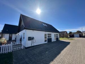a white building with a black roof and a driveway at Guesthouse Villa Sønderklit in Skagen