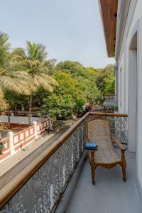 a chair sitting on a balcony looking out at the trees at Le Dupleix in Pondicherry