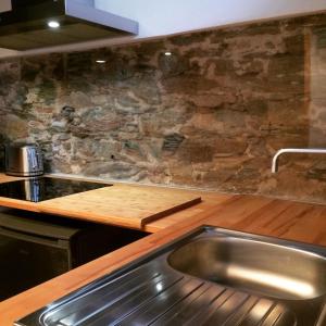 a kitchen with a sink and a stone wall at Domaine Santa Petronilla "chapelle" in Rogliano