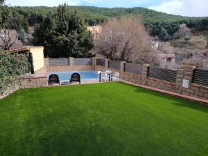 a large yard with a swimming pool with green grass at Casa La Rubía de Gredos in Cuevas del Valle