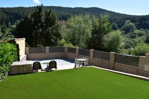 a patio with two chairs and a table and grass at Casa La Rubía de Gredos in Cuevas del Valle