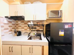 a kitchen with a sink and a black refrigerator at RR 21 Milan Residenze Fairview in Manila