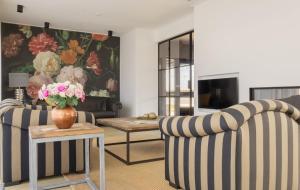 a living room with two chairs and a vase of flowers at Villa Verderop - Luxury Lakeside Villa with Terrace & Water Views in Friesland in Boornzwaag