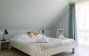 a white bedroom with a white bed and a window at Villa Verderop - Luxury Lakeside Villa with Terrace & Water Views in Friesland in Boornzwaag