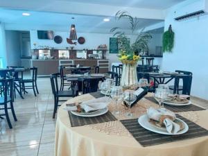 a dining room with a table with plates and wine glasses at Hotel Cajuína Beach in Parnaíba