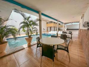 a room with tables and chairs and a swimming pool at Hotel Cajuína Beach in Parnaíba