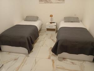 two beds in a room with marble floors at Il-Pitirross Apartment Gozo in Sannat +13 photos