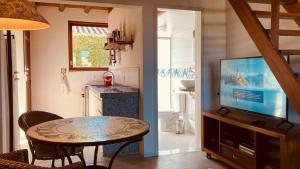 a living room with a table and a television at Flats Bon Voyage Caboré - Chez Cira in Paraty