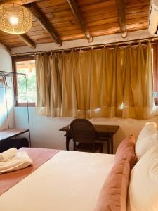 a bedroom with a bed and a table and a window at Flats Bon Voyage Caboré - Chez Cira in Paraty