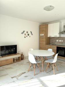 a dining room with a white table and chairs at Il-Pitirross Apartment Gozo in Sannat