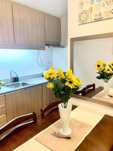 a kitchen with a table with yellow flowers in a vase at Casa Cozy Condo Davao in Davao City