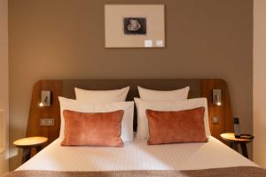 a bedroom with a bed with white sheets and orange pillows at Europe Hotel Paris Eiffel in Paris