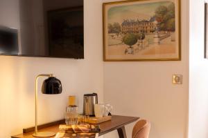 a table with a lamp and a picture on the wall at Europe Hotel Paris Eiffel in Paris