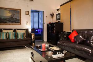 een woonkamer met een leren bank en een tafel bij Frangipani Penthouse in New Delhi