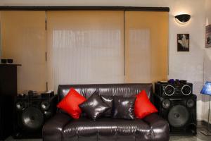 een woonkamer met een leren bank en luidsprekers bij Frangipani Penthouse in New Delhi +26 foto's