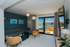 a living room with a couch and chairs and a large window at áPero Suites in Trogir