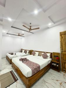 two beds in a bedroom with a ceiling fan at Hotel Shiva Darshanam in Varanasi