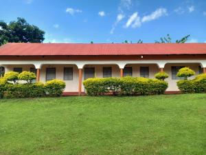 a building with a red roof and a green yard at Yasipi Cottages in Sipi