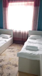 two beds in a room with a window at 3 room SUPERIOR APARTMENT at ELITE TOWER in downtown NURBIE'S TRAVEL in Ölgiy