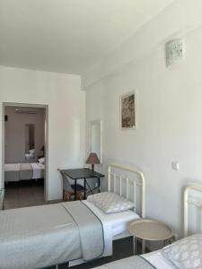 a bedroom with two beds and a table and a desk at Annalisa Studio & Apartments in Skala