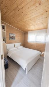 a large white bed in a room with a wooden ceiling at Private Wood Cabin in Palanga