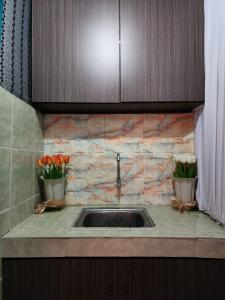 a kitchen counter with a sink and two vases of flowers at CBR Beach in Kota Belud