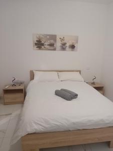 a bedroom with a white bed with two tables at Il-Pitirross Apartment Gozo in Sannat
