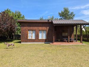 a dog running in front of a small house at Private Wood Cabin in Palanga
