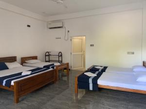 a room with two beds and a door in it at Grace Inn in Kalkudah