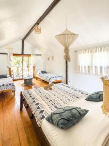 two beds in a room with white walls and wooden floors at Lodge Océan et Savane in Saint-Louis