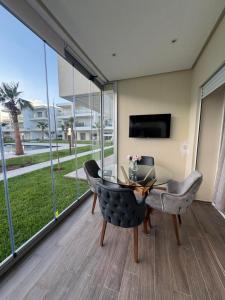 a dining room with a glass table and chairs at Cozy apartment with pool view in Dar Hamida