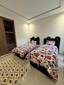 a bedroom with two beds and a carpet at Cozy apartment with pool view in Dar Hamida