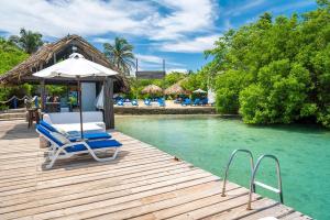 a wooden deck with chairs and an umbrella on the water at Bayside Island in Cartagena de Indias